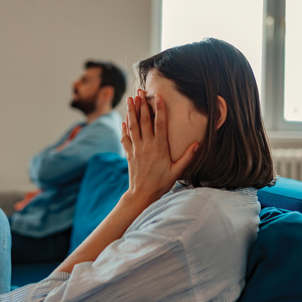 Woman covering face on a couch